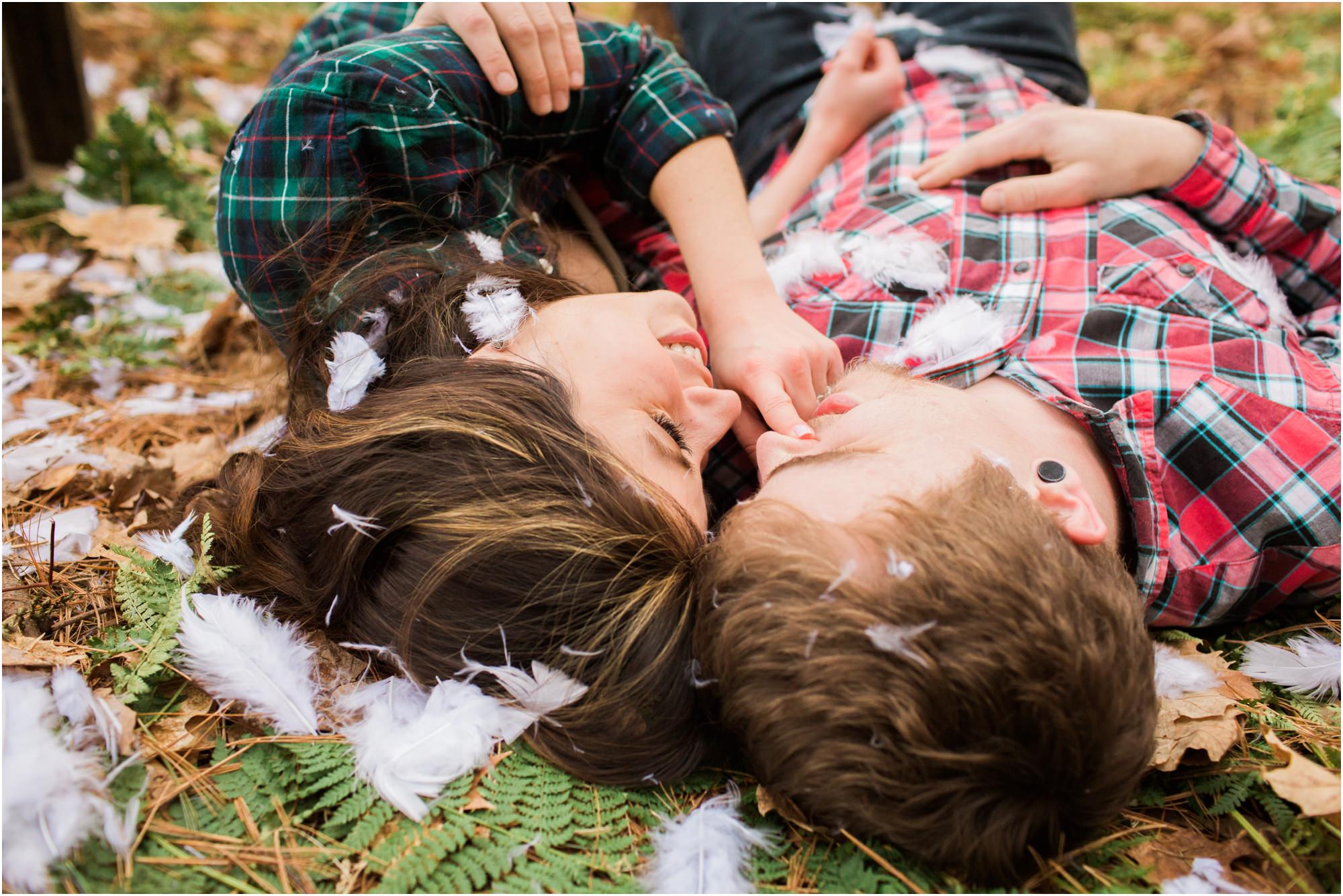 couple laying in the woods after pillow fight engagement session