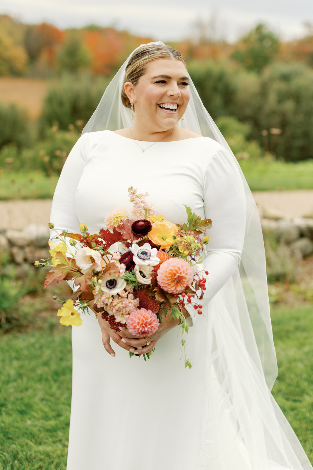 Bride in wedding gown holding bouquet and laughing at Inn by the Sea