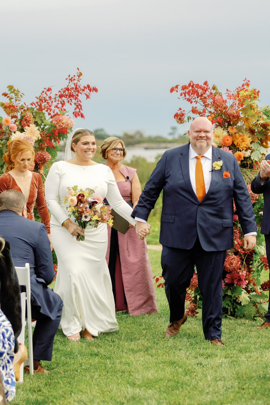 Fall wedding at Inn by the Sea in Maine. Couple leaving their wedding ceremony in front of floral arch.