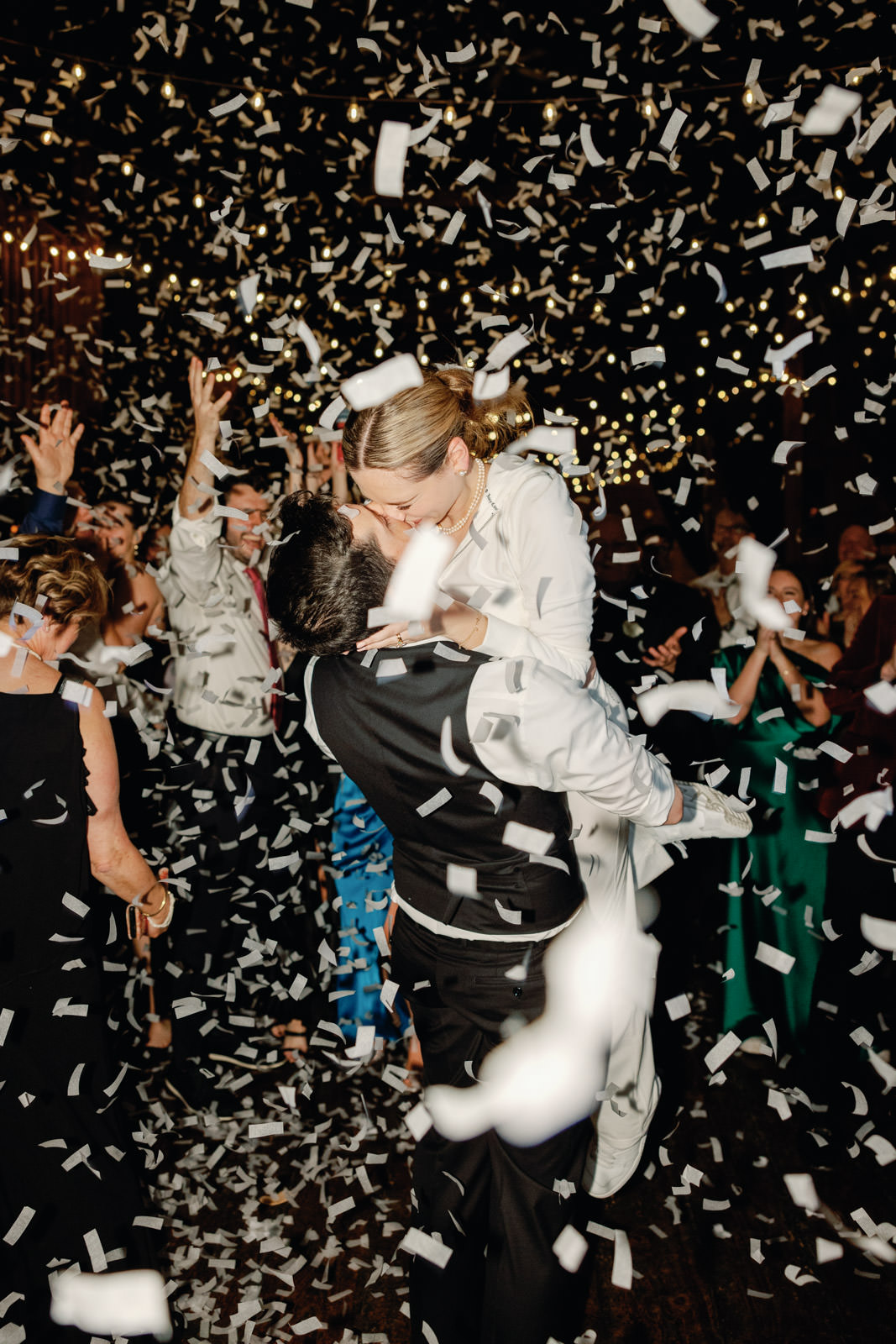 Couple kissing at their wedding reception while confetti falls at The Barns at Wesleyan Hills