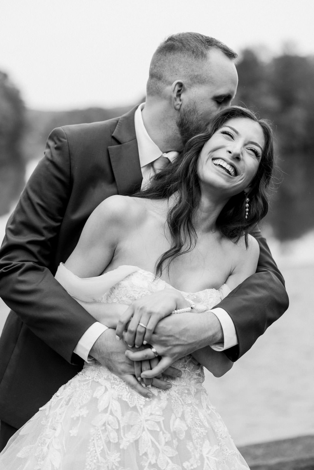 Connecticut wedding photographers, May wedding at Pavilion on Crystal Lake. Couple in wedding attire laughing in front of lake.